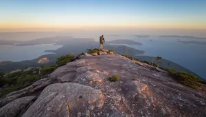 Hiker on Cadillac Mountain South Ridge Trail summit in Acadia National Park overlooking Frenchman Bay and the offshore islands